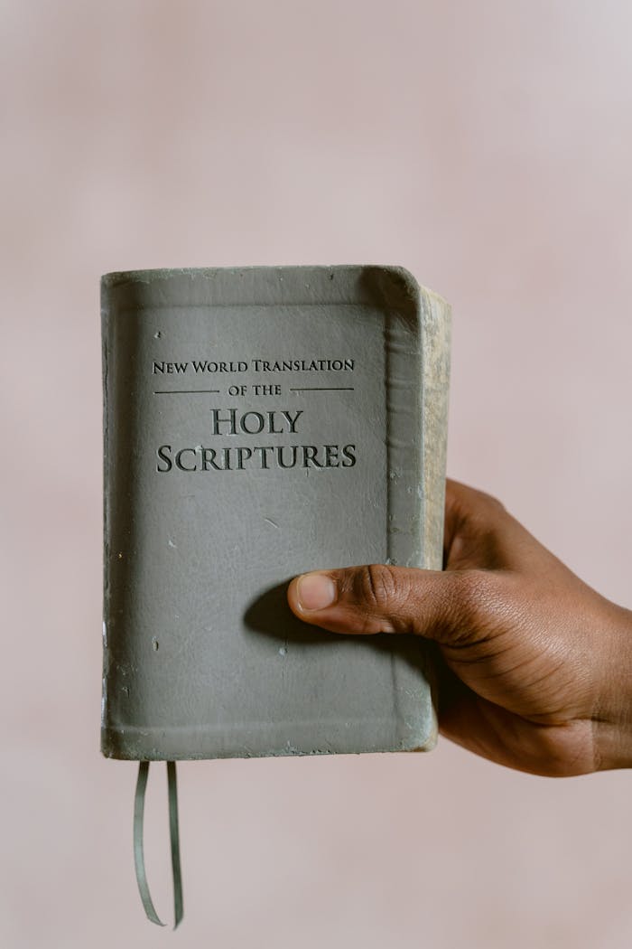 Close-up of a hand holding the Holy Scriptures, focusing on religious and spiritual themes.