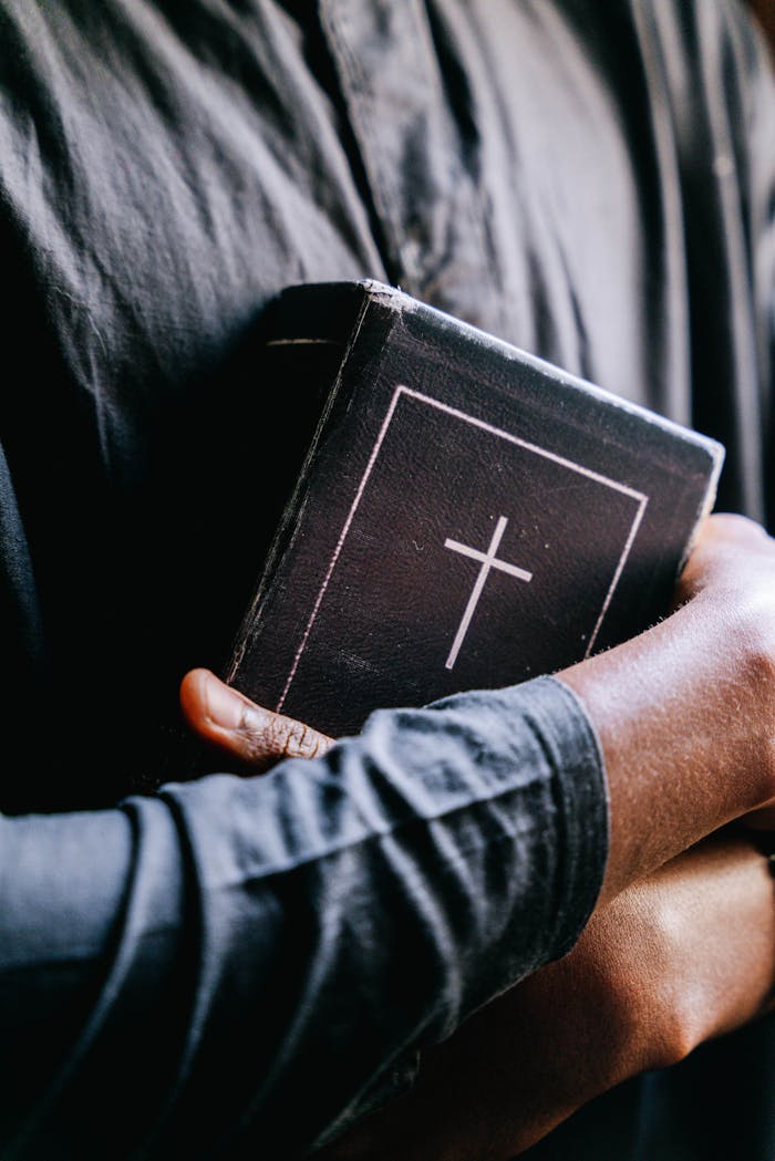 Close-up of a person holding a holy bible with a cross, focusing on religion and faith.